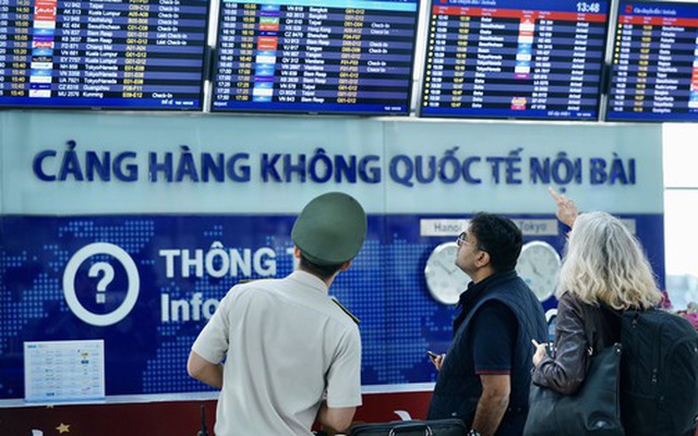 Nhân viên an ninh hỗ trợ hướng dẫn hành khách chuyến bay quốc tế tại sân bay Nội Bài - Ảnh: Phan Công