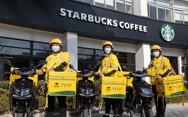Các nhân viên giao đá lạnh của ứng dụng Meituan đứng trước một cửa hàng Starbucks ở Thượng Hải - Ảnh: SCMP