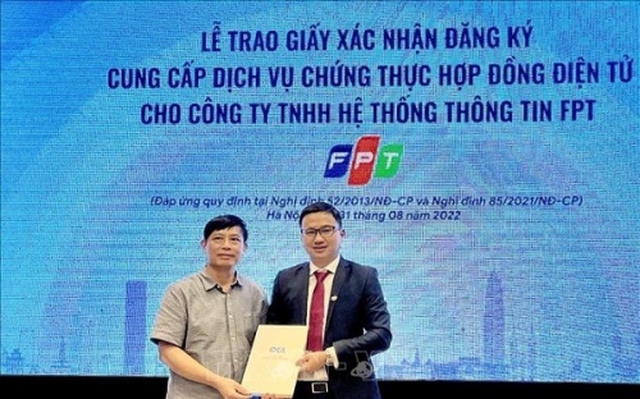 Cục trưởng Cục Thương mại điện tử và Kinh tế số Đặng Hoàng Hải trao Giấy xác nhận đăng ký cung cấp dịch vụ chứng thực hợp đồng điện tử cho ông Thân Minh Ngọc, PGĐ Khối Doanh nghiệp, Công ty Hệ thống Thông tin FPT. Ảnh: TTXVN