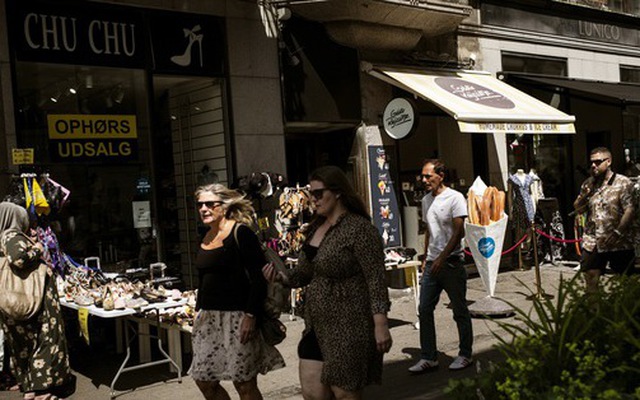 Người đi đường đi qua các cửa hàng ở thủ đô Copenhagen, Đan Mạch - Ảnh: Bloomberg