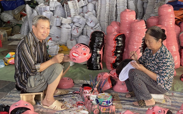 Vợ chồng nghệ nhân Vũ Huy Đông sơn màu những chiếc mặt nạ giấy bồi cho chuyến hàng Tết Trung thu.
