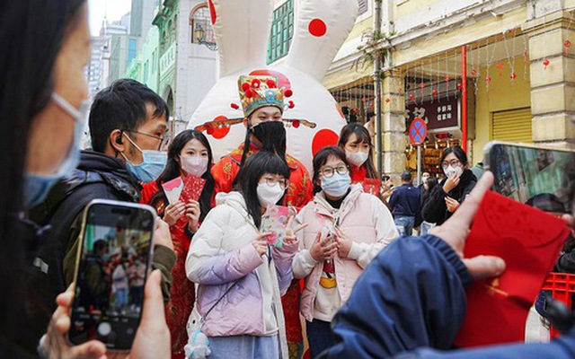 Người dân đeo khẩu trang chụp hình với người hóa trang Thần Tài trong dịp Tết Nguyên đán ở Macau ngày 25-1 - Ảnh: REUTERS