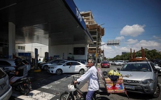 Người đi xe máy chờ đổ xăng ở Buenos Aires (Argentina) giữa lúc các công ty dầu nước này đồng loạt tăng giá. Ảnh: REUTES.