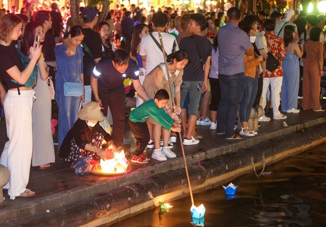 Tourists walk around Hoi An ancient town, waiting in long queues to drop flower lanterns on Tet holiday - Photo 10.