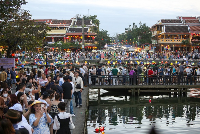 Tourists walk around Hoi An ancient town, waiting in long queues to drop flower lanterns on Tet holiday - Photo 6.