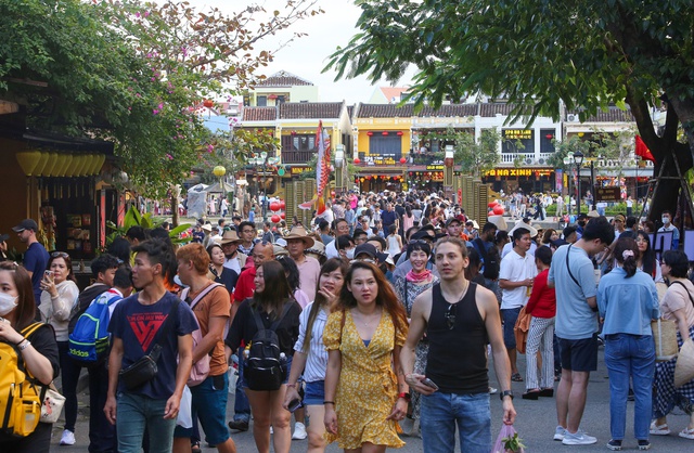 Tourists walk around Hoi An ancient town, waiting in long queues to drop flower lanterns on Tet holiday - Photo 4.