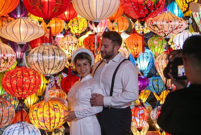 Tourists walk around Hoi An ancient town, waiting in long queues to drop flower lanterns on Tet holiday - Photo 17.