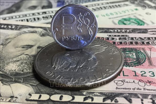 Đồng xu ruble của Nga (phía trên) và đồng bạc xanh Mỹ tại Moskva, Nga. Ảnh: AFP/TTXVN