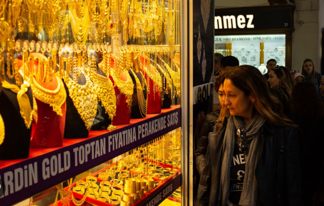 Một số phụ nữ đi ngang qua tủ kính trưng bày đồ trang sức bằng vàng ở Grand Bazaar, Istanbul. Ảnh: Getty Images