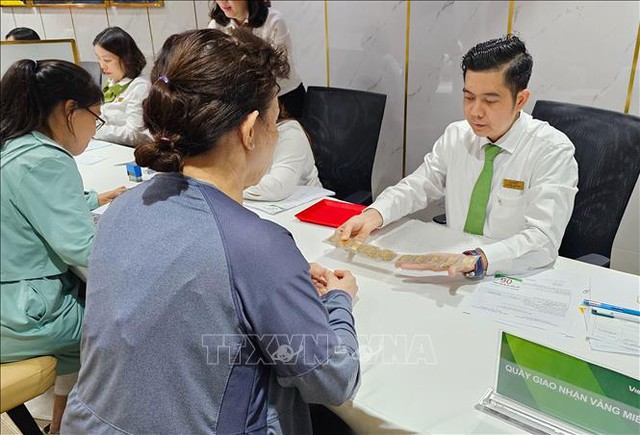 Khách hàng mua vàng miếng thực hiện giao dịch tại Ngân hàng Vietcombank ở TP Hồ Chí Minh. Ảnh: Thanh Vũ/TTXVN