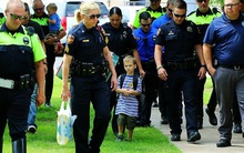 Câu chuyện buồn đằng sau bức hình em bé 4 tuổi đi khai giảng với 18 cảnh sát theo sau