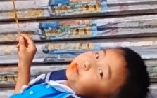 Mẹ đến đón muộn, cậu bé thản nhiên nằm trên bậc thềm ăn đồ ăn: Dân mạng bật cười vì quá chill!