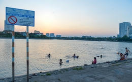 Giữa trời nắng chang chang, bất chấp biển cấm, người dân đội nón bơi ra giữa hồ Linh Đàm