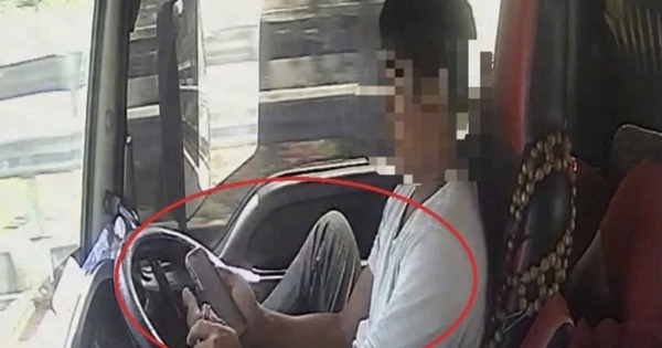Tài xế dùng chân điều khiển xe đầu kéo chạy trên cao tốc, tay cầm điện thoại lướt TikTok